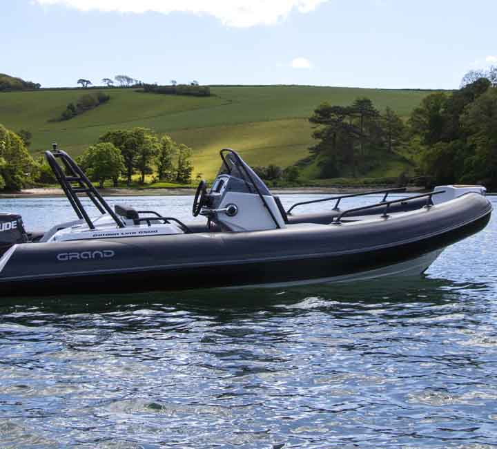 A Grand G500 sat on the water, featuring dark tubes and a ski arch at the stern