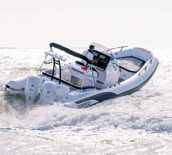 A white Grand G850 with a passenger on board driving the boat through clear water