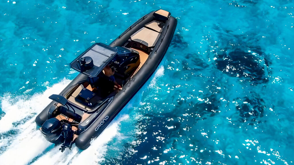 A Grand G850 - one of Grand's large adventure RIBs - on light blue water, with black hypalon tubs and tan interiors