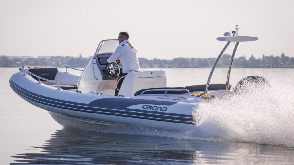 A Grand G650 with white tubes moving through the water with a driver at the helm