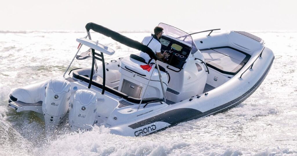 A Grand G850 with white tubes and two twin Yamaha 200HP engines on the back, travelling on the water