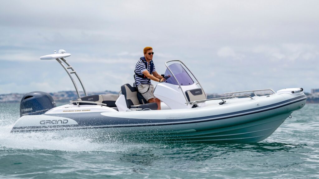 An image of a runabout boats - the Grand G580 on the water with a male driver at the helm of the boat.