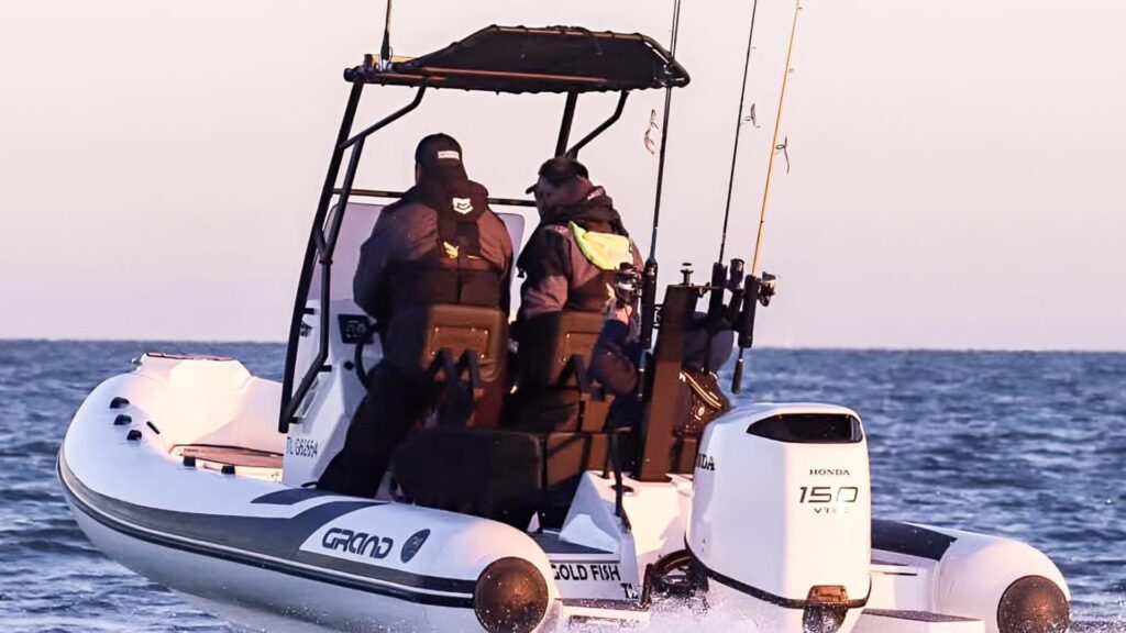 A Grand D600 inflatable fishing boat in white with two passengers on board and rods at the stern and on the t-top