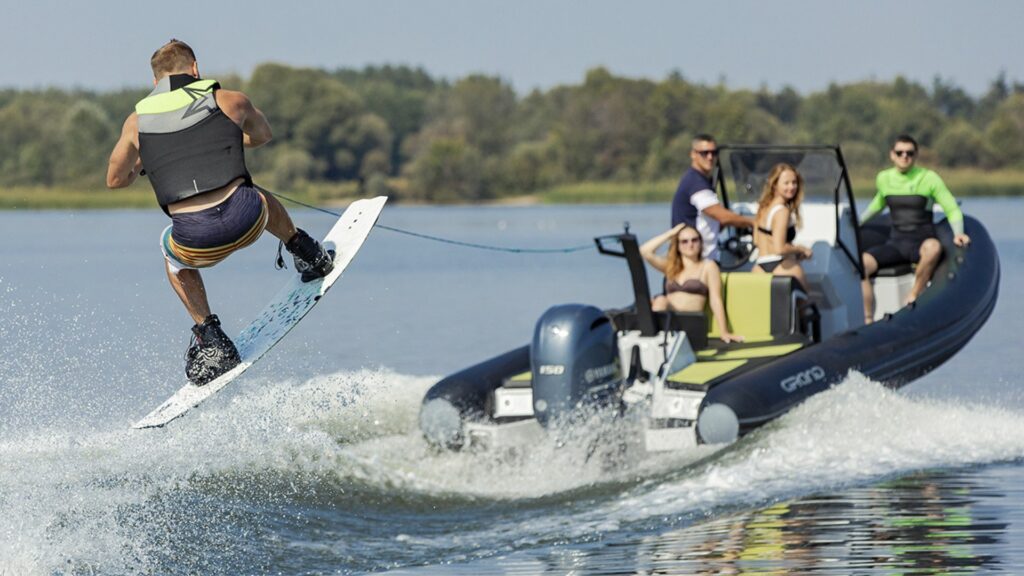 Grand D600 wakeboarding boat with a group on board, and a wakeboarder in the air behind