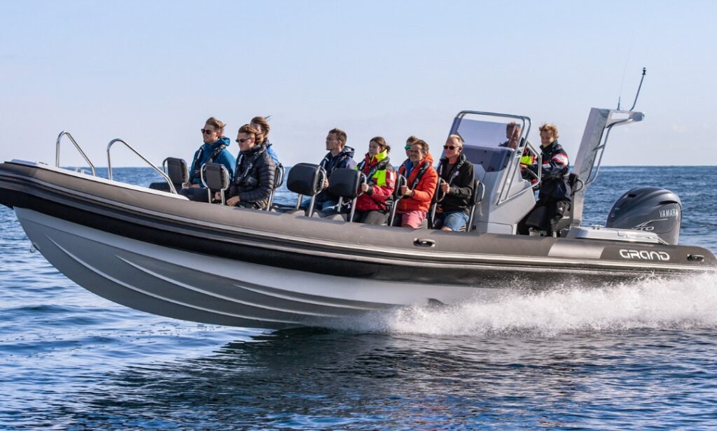 10 passengers onboard a black RIB boat travelling through the water - one of the best rigid inflatable boat for commercial use