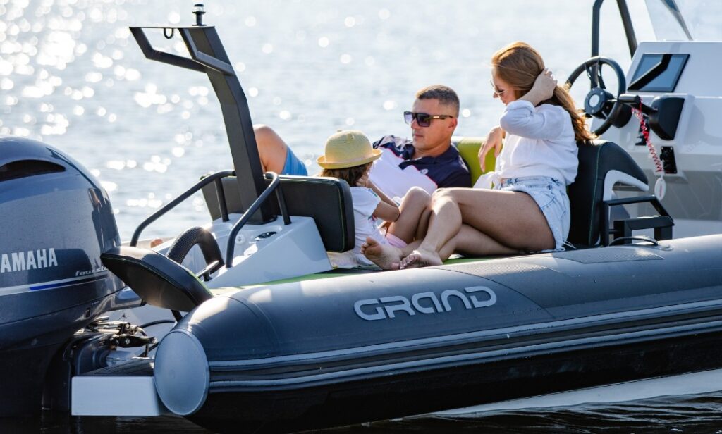 A family of three sat at the back of a boat in the sunshine