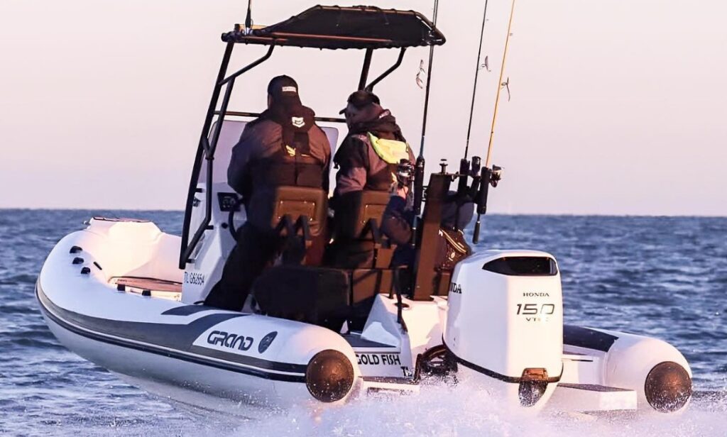 Two passengers onboard a Grand D600 RIB boat with fishing rods on the back