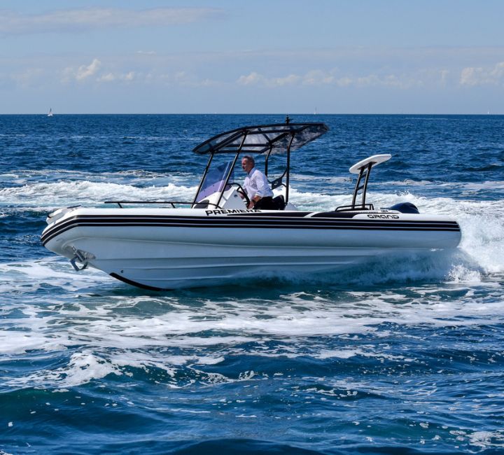 Grand G680 with white tubes turning on an angle in the water, a passenger onboard driving under a t-top