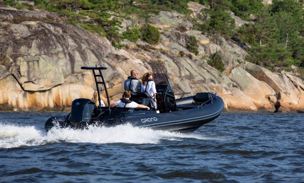 A family of four sitting on a black rigid inflatable boat as it travels on the water