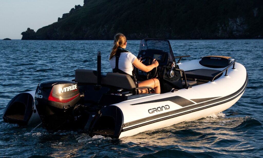 A small white and black rigid inflatable boat in the sunset