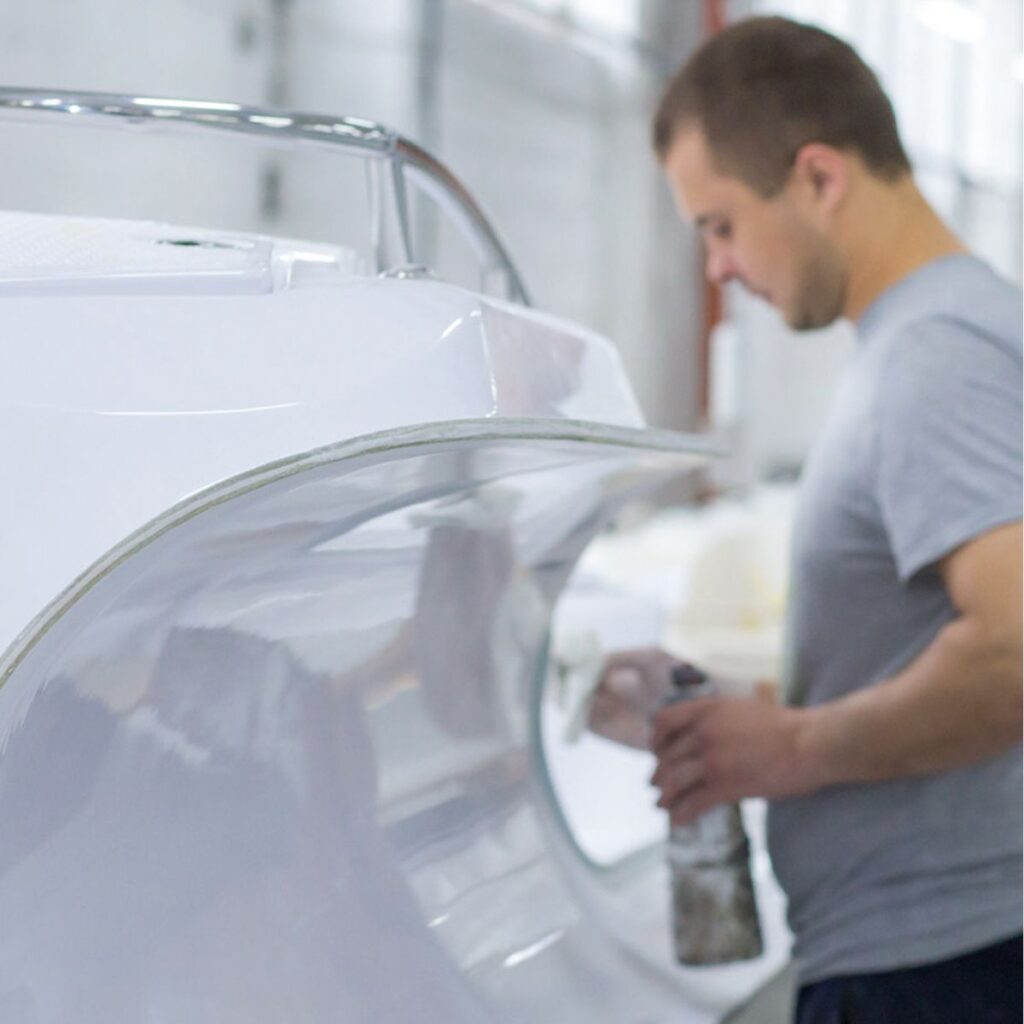 A Grand Inflatable Boats employee cleaning a white fibreglass boat