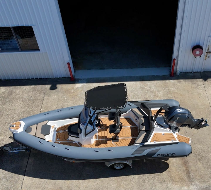 A grey rigid inflatable boat from above, showing the brown and black flooring