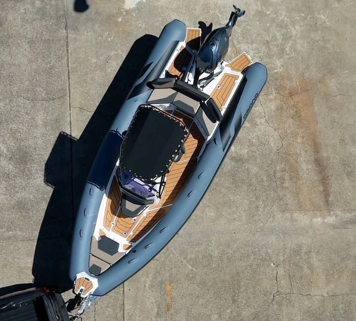 A grey rigid inflatable boat from above, showing the brown and black flooring