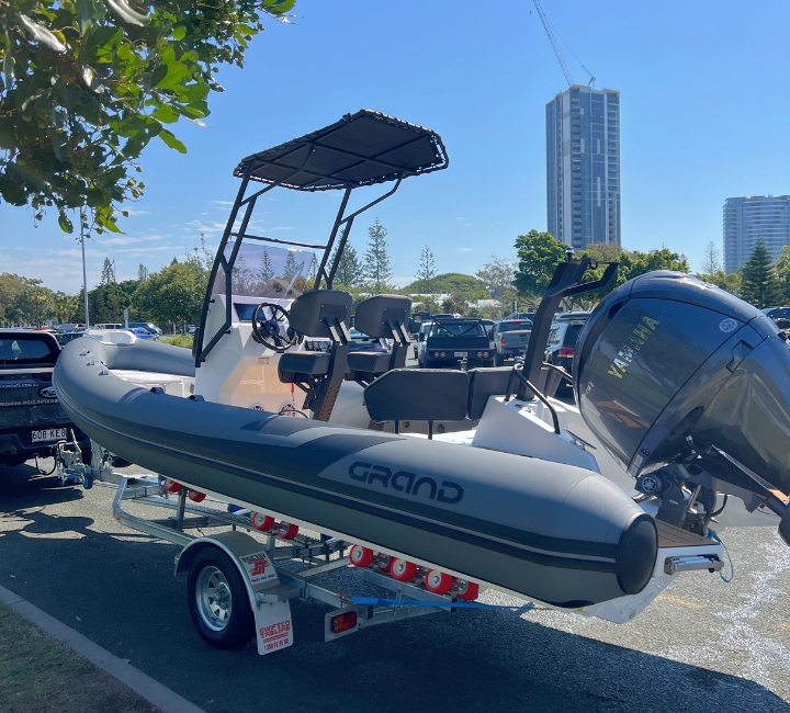 A dark grey rigid inflatable boat with Yamaha engine being towed behind a boat