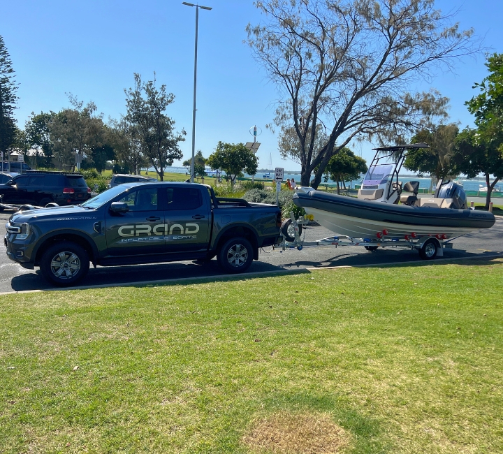 A dark grey rigid inflatable boat with Yamaha engine being towed behind a boat