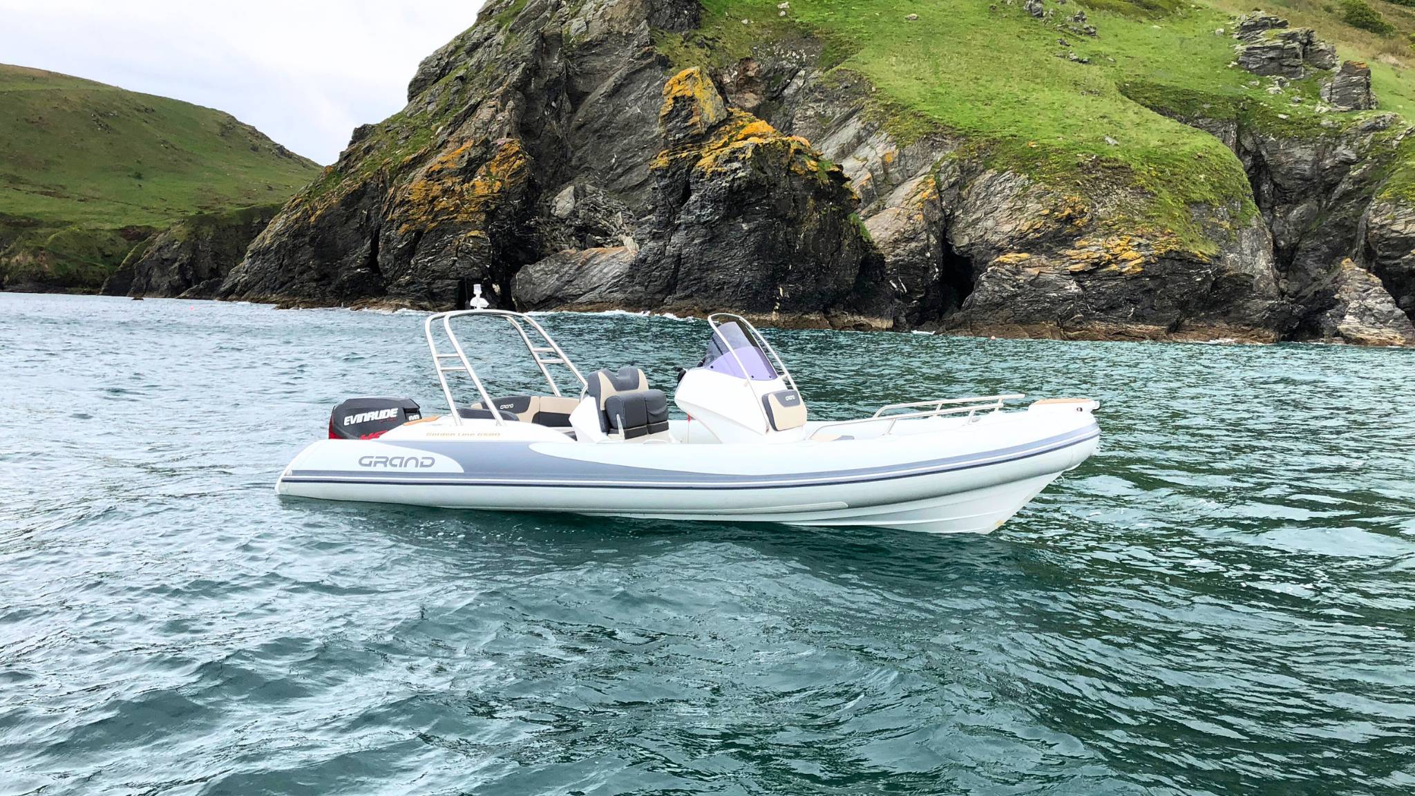 A Grand G580 boat sat on the water near a cliff