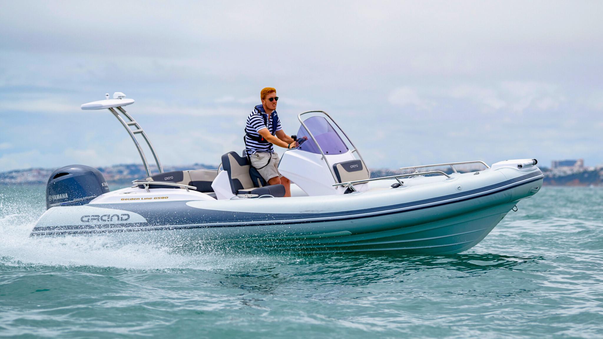 A Grand G580 boat being driven on the water with a male passenger onboard