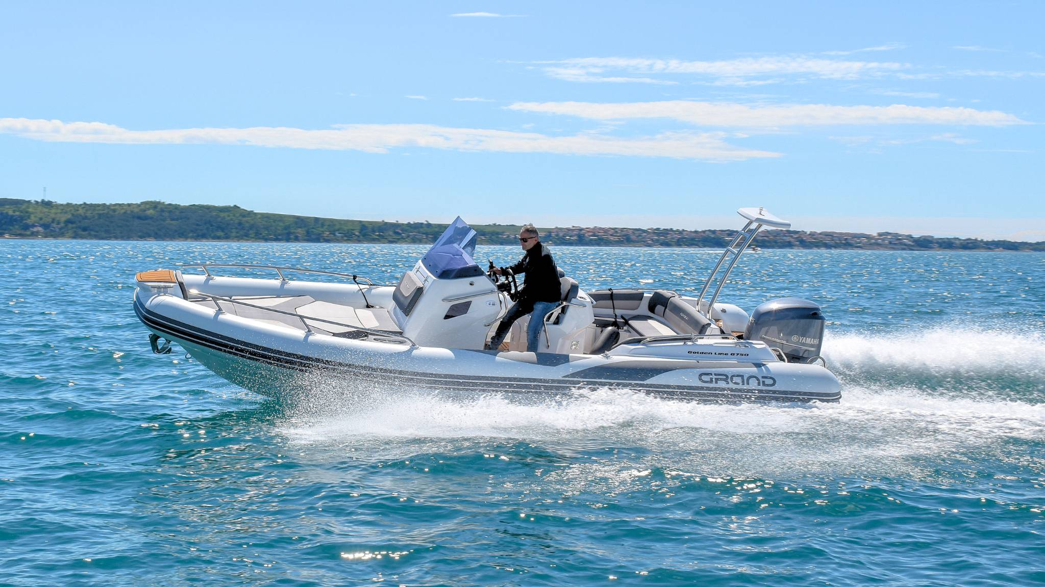 A Grand G750 rigid inflatable boat on the water with a man driving