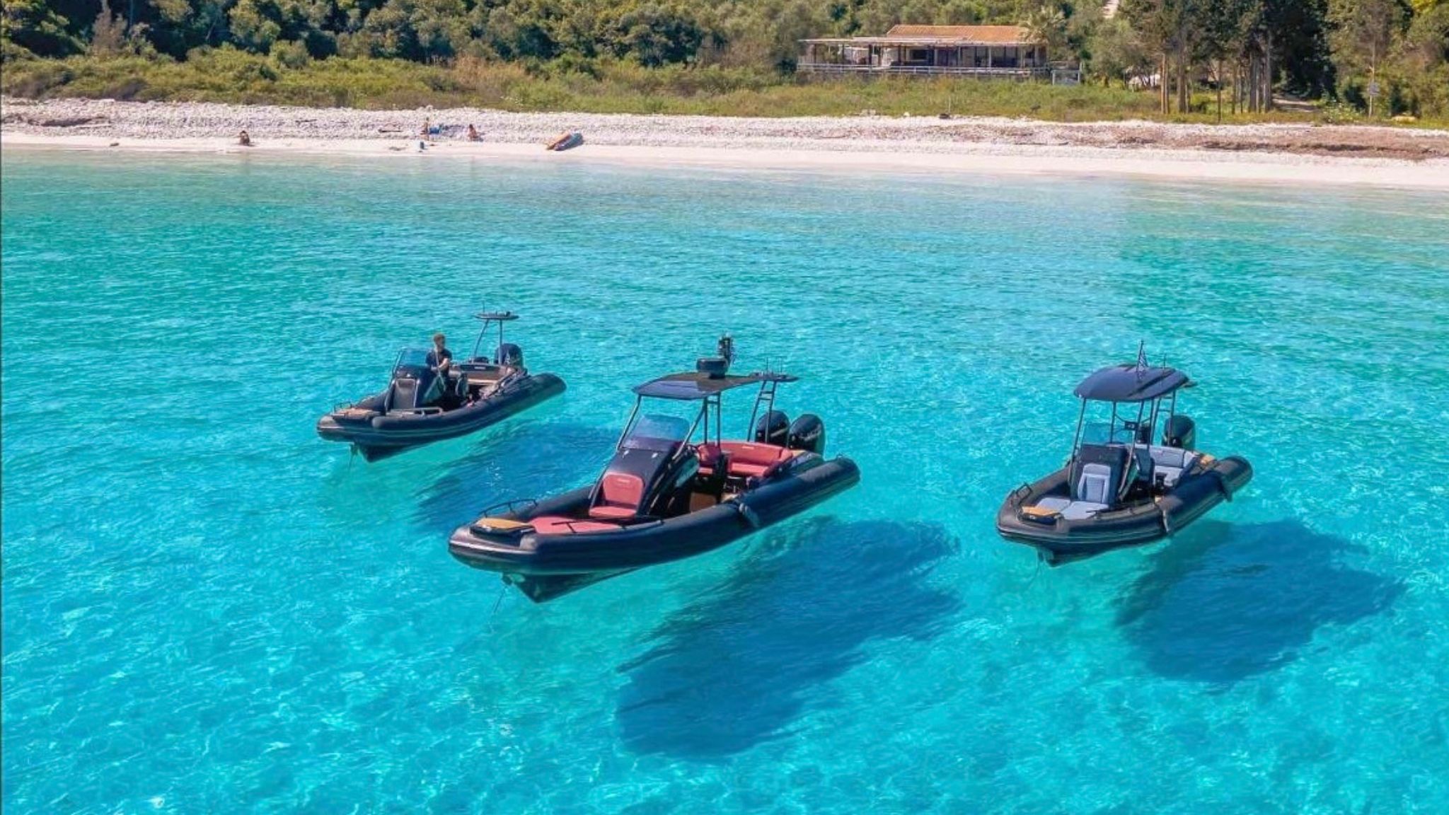 Three rigid inflatable boats moored in crystal clear blue water