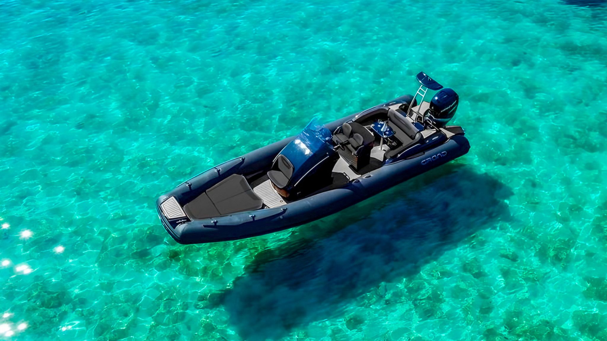 A black Grand G850 rigid inflatable boat floating in clear blue waters