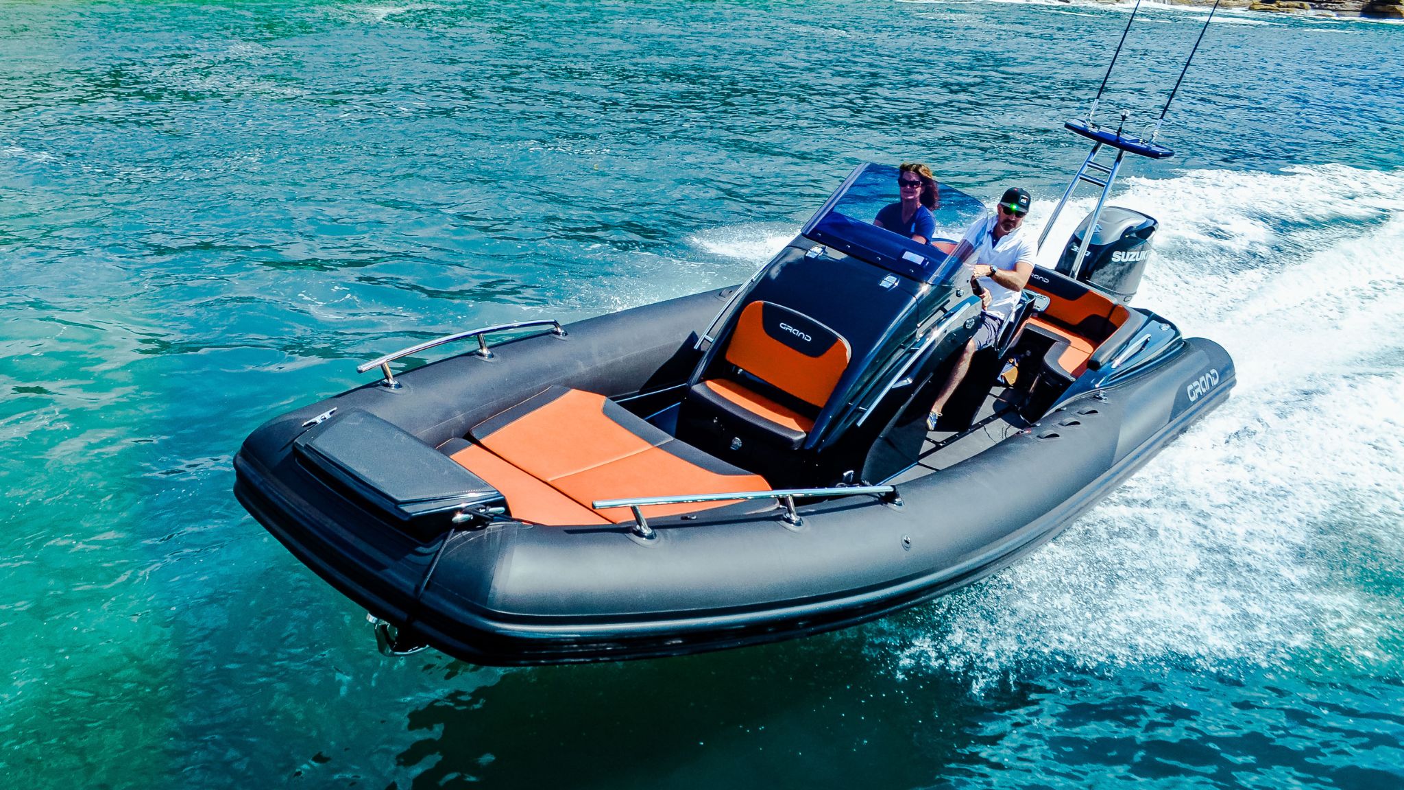 A black G850 rigid inflatable boat with two passengers on board travelling through the water