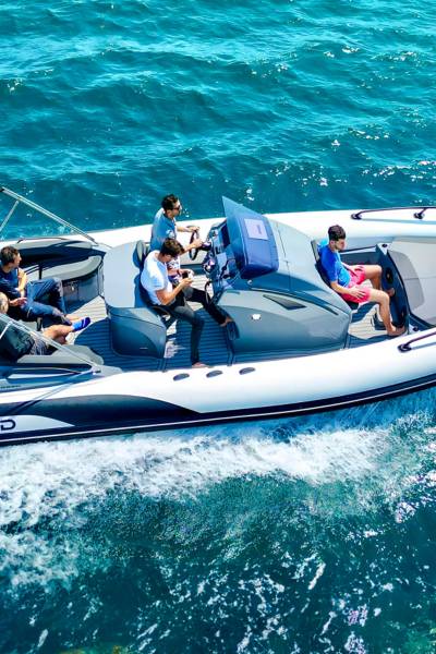 A white and grey Grand G850 rigid inflatable boat travelling through the water with five passengers on board