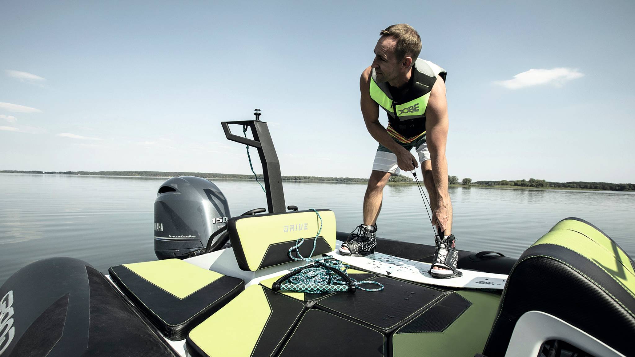 A man putting on wakeboarding equipment at the back of the Grand D600 rigid inflatable boat