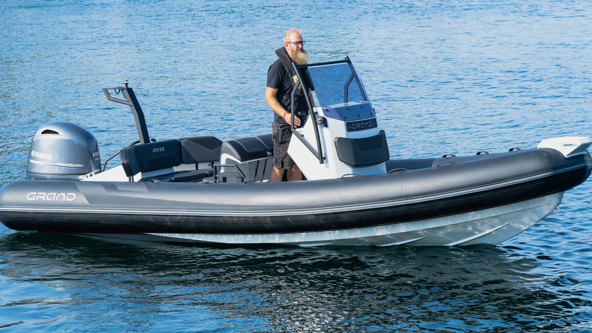 A man driving a Grand D600 inflatable boat, standing at the helm