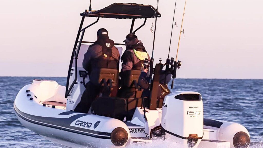 Two drivers at the helm of the Grand D600 boat with fishing rods at the stern of their boat