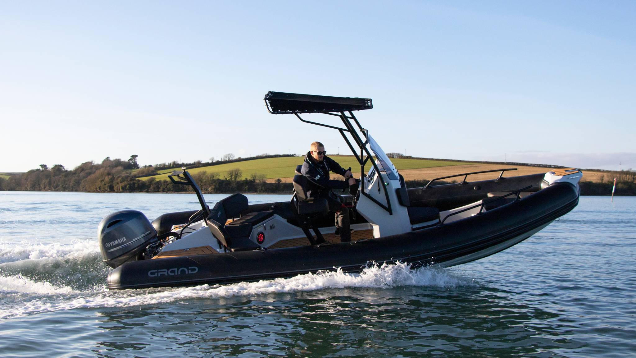 A man driving a Grand D600 boat, turning the boat around a corner