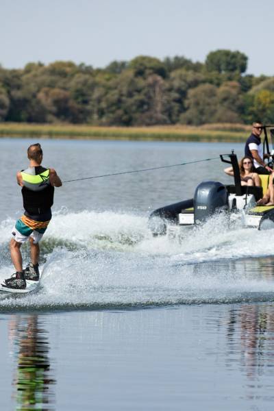 A wakeboarder behind a Grand D600 boat with passengers onboard watching