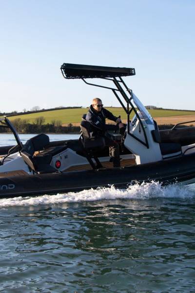 A man driving a Grand D600 boat, turning the boat around a corner