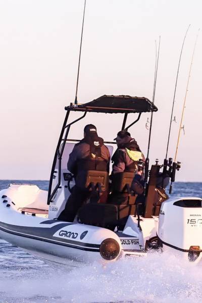 Two drivers at the helm of the Grand D600 boat with fishing rods at the stern of their boat