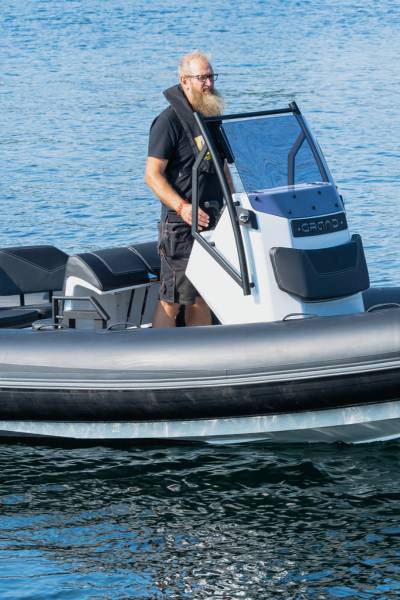 A man driving a Grand D600 inflatable boat, standing at the helm