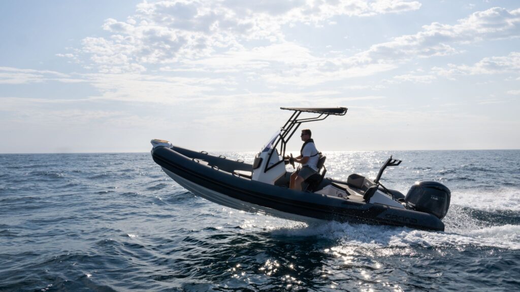 A Grand D600 rigid hull inflatable boat jumping out of the water with a passenger on board