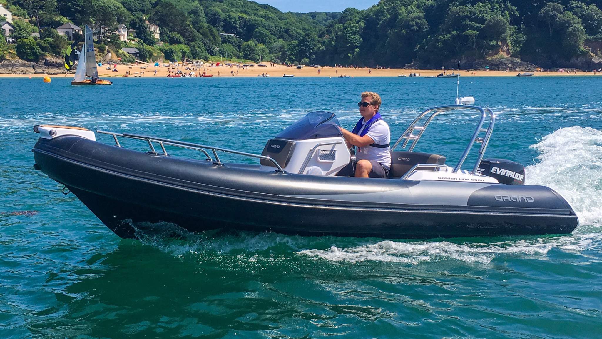 A male driving a Grand G500 boat on the water