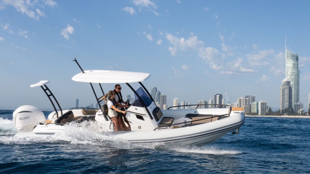 Grand G750 RIB boat on the water with a cityscape in the background, two passengers on board