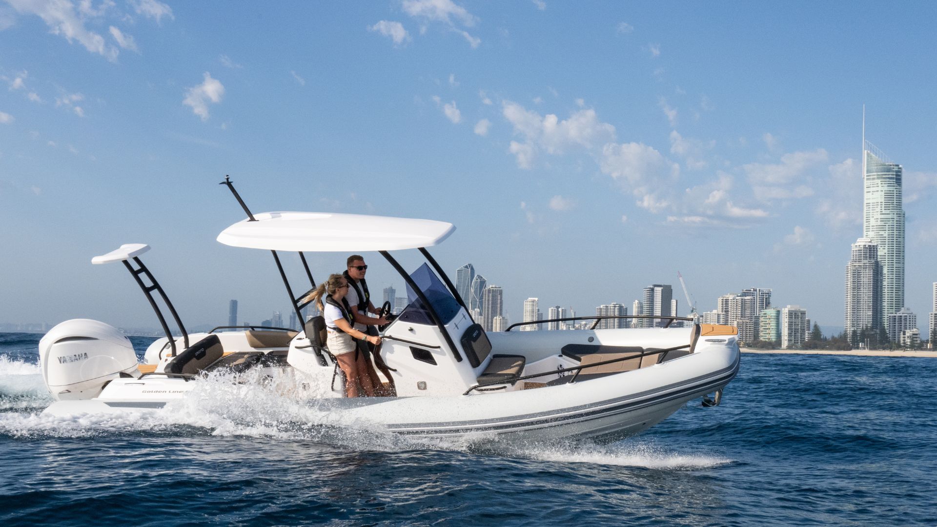 Grand G750 RIB boat on the water with a cityscape in the background, two passengers on board