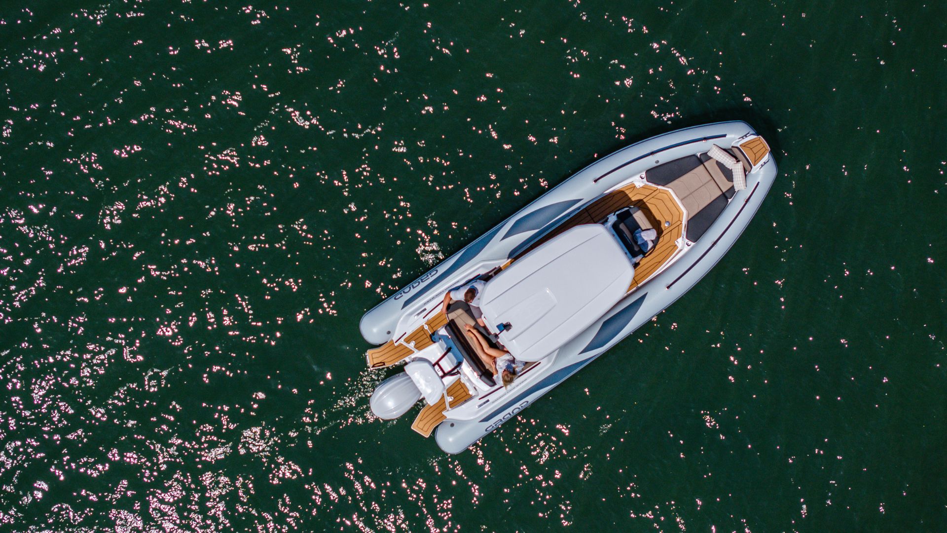 Grand G750 sat on the water with two passengers relaxed on the stern of the boat