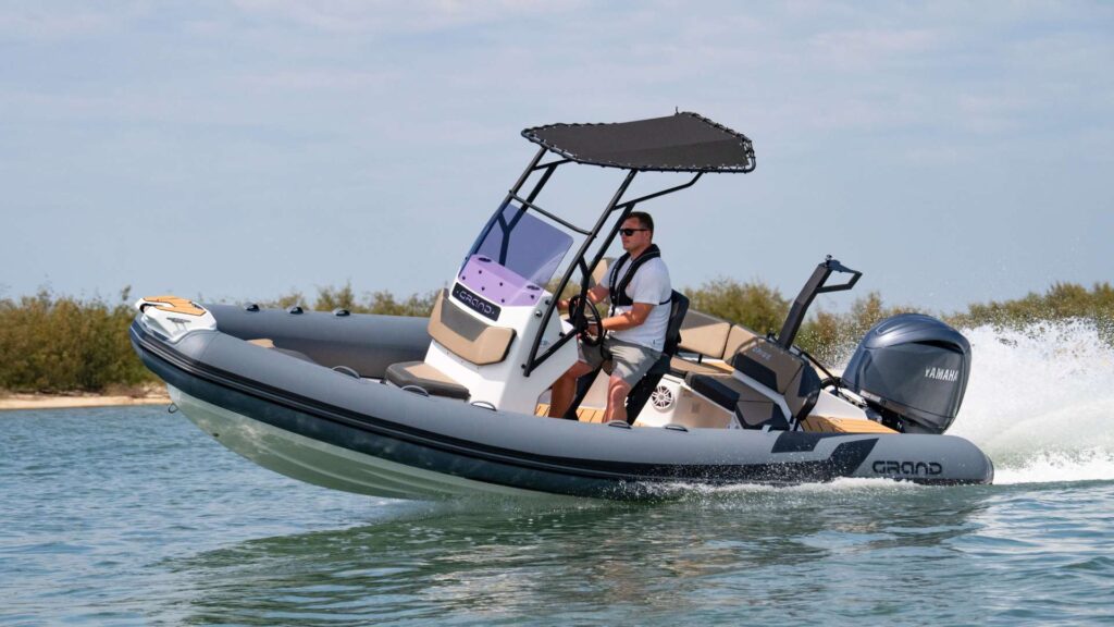 A Grand D600 rigid inflatable boat on the water with dark grey inflatable tubes