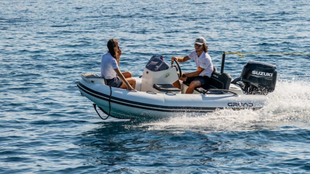 The Grand G340 tender boat with two passengers onboard, towing an inflatable behind