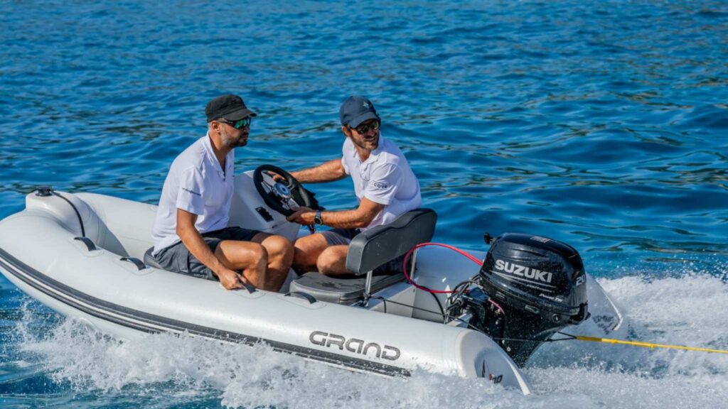 A Grand G330 tender boat with two passengers on board, towing an inflatable behind them