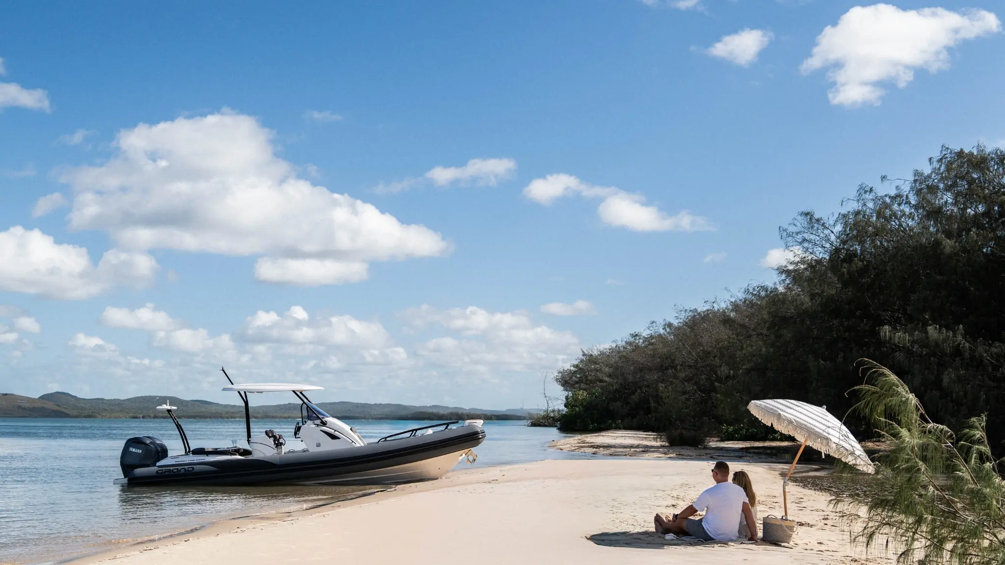 Grand G850 rigid inflatable boat on the beach with a couple sat on the sand
