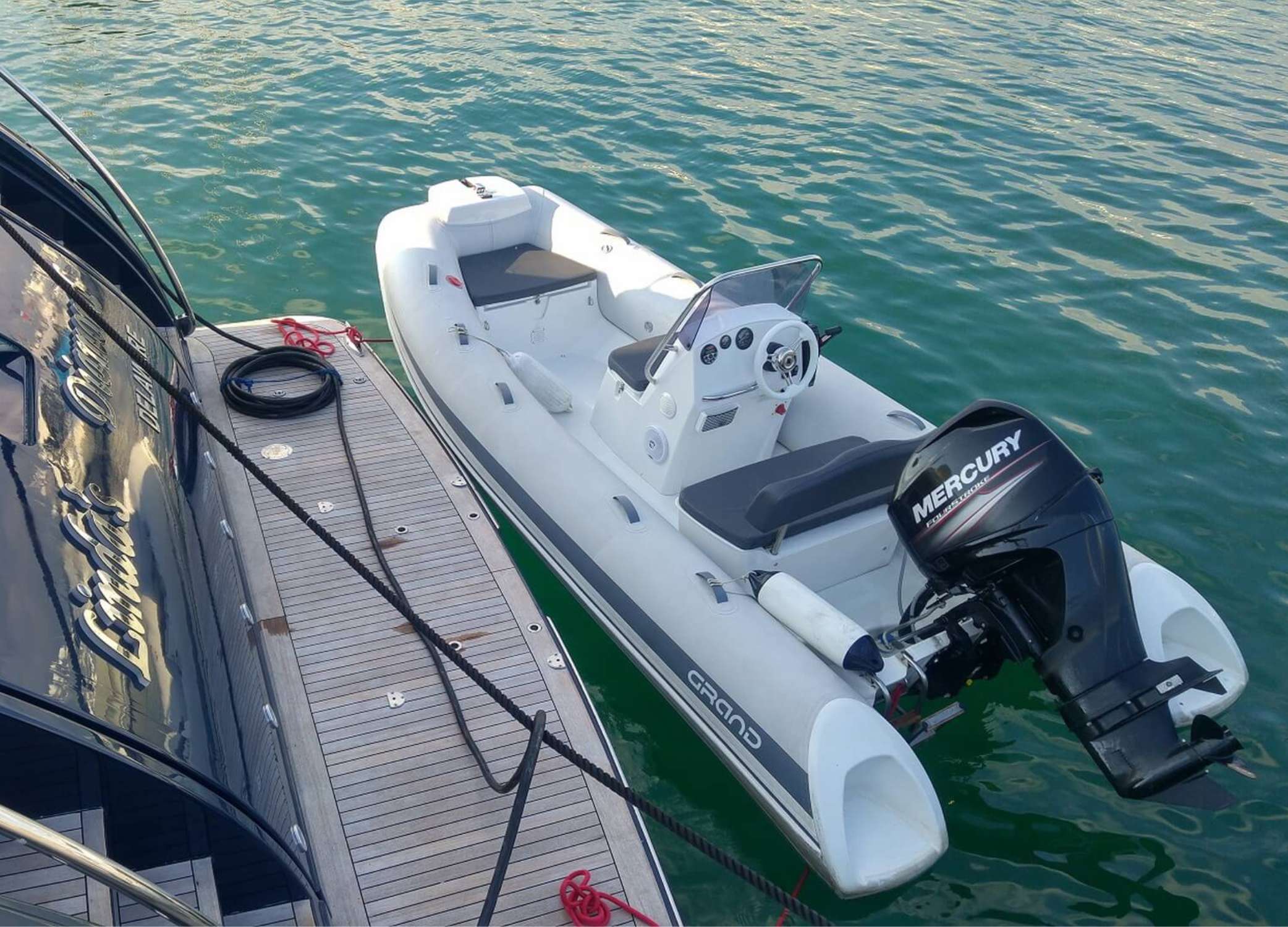 The Grand S470 tender boat moored next to a large yacht