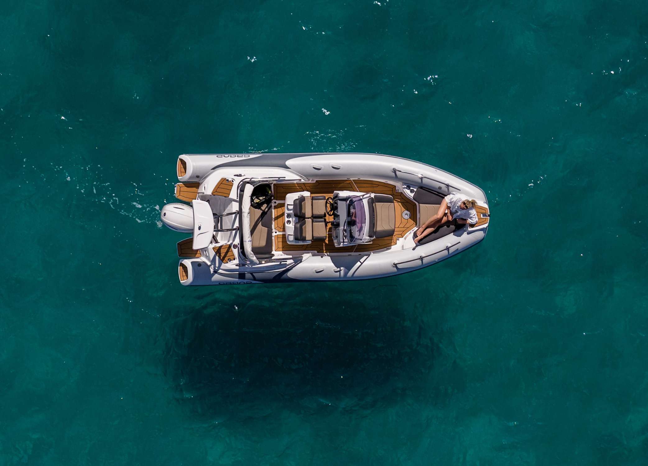 Grand G580 rigid inflatable boat on the water with a woman sat at the bow sun bed