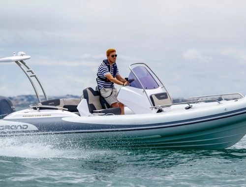 An image of a runabout boats - the Grand G580 on the water with a male driver at the helm of the boat.