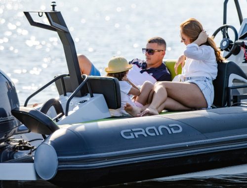 A family of three sat at the back of a boat in the sunshine