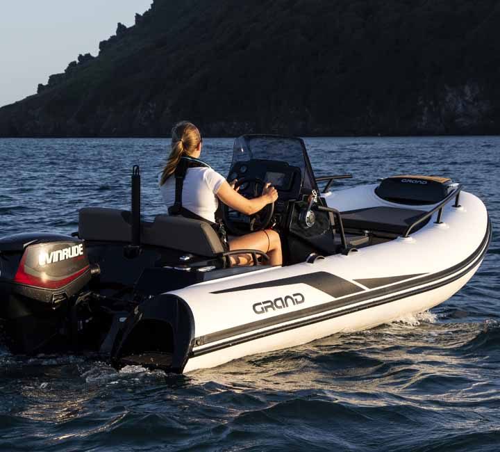 A female passenger driving a white Grand G420 at sunset