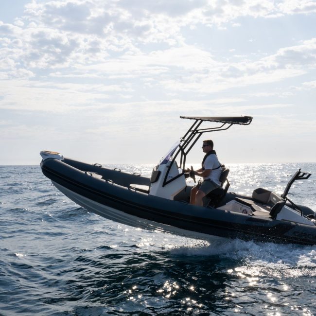 A Grand D600 rigid hull inflatable boat jumping out of the water with a passenger on board