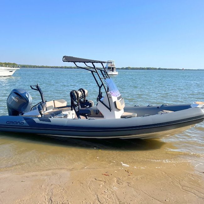 The Grand D600 for sale with dark grey tubes and a t-top with Yamaha 150HP outboard sitting on the beach